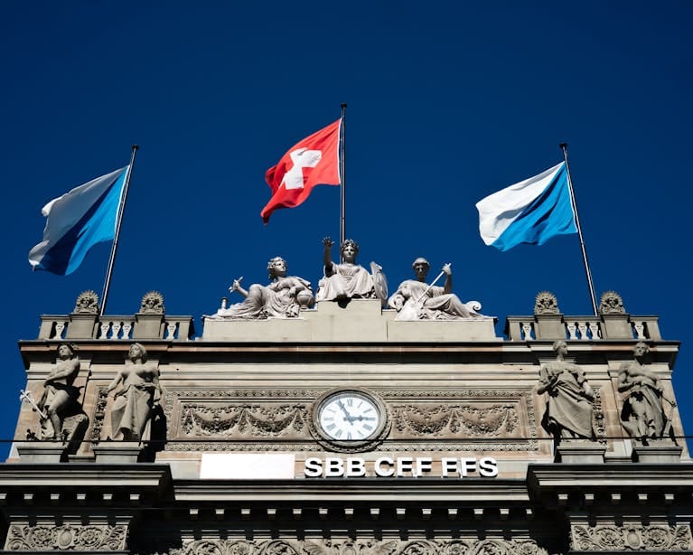Historic SBB building with Swiss flags and sculptures in Zurich.